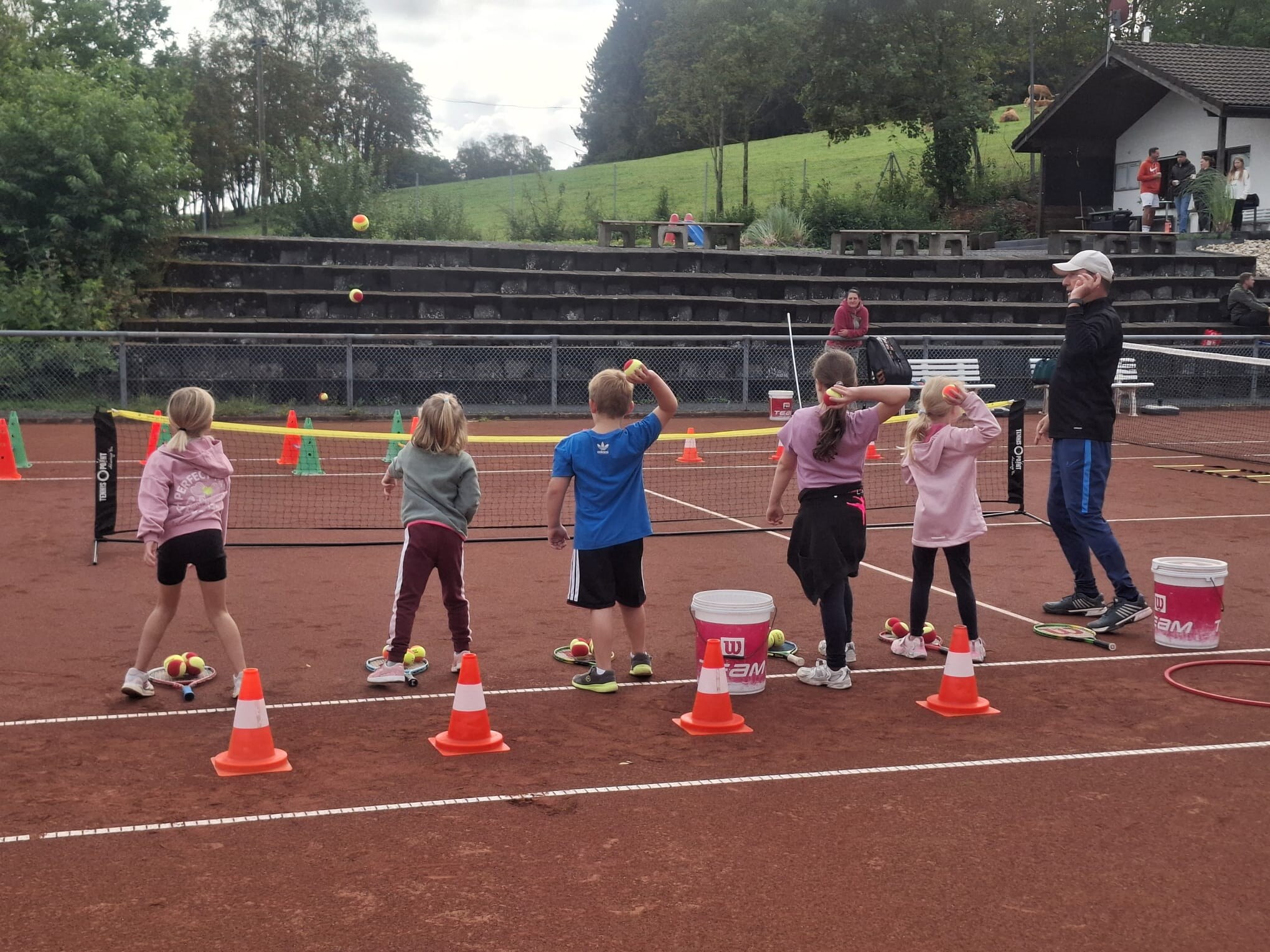 Kinder probieren gemeinsam eine Wurfübung mit Bällen aus